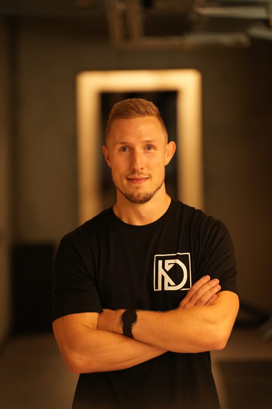 Portrait von Dietmar Kühnel mit verschränkten Armen im Trainingsstudio.